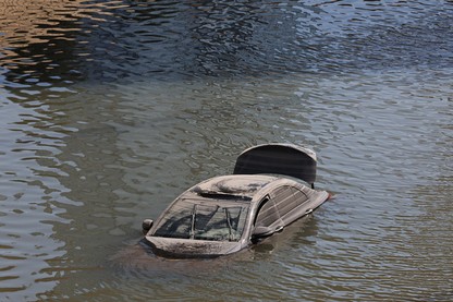 An abandoned vehicle floats in floodwater.