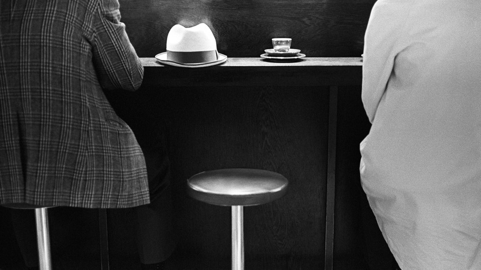 An empty stool in between two people at a dining establishment