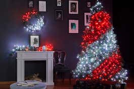 A room decorated using Twinkly Smart String Lights, including a Christmas tree with red and white lights forming a candy cane twist, plus a red and white design on the mantlepiece.