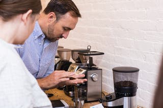 A person with looking at coffee grounds in their hand.