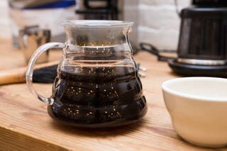 A half filled pot of coffee on a kitchen counter.