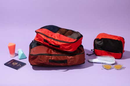 One of the packing cube sets that we tested to find the best, filled with clothes and shown with a passport and sunglasses.