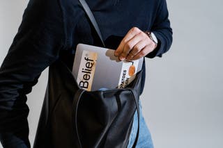 A person pulling a laptop out of the Leatherology tote.