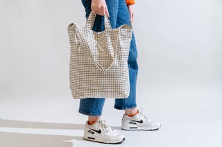 a person holds the Baggu duck bag by its handles.