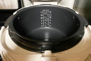 The nonstick interior of the Cuckoo CRP-P1009. There are rice measurements printed on the inside wall of the pot.