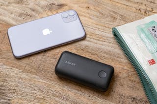 An iPhone and an Anker PowerCore 10000 PD Redux portable charger resting on a table.