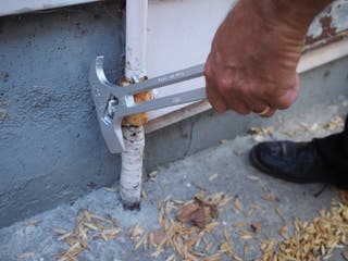 A person's hand using a water and gas shutoff tool to turn off their household gas.