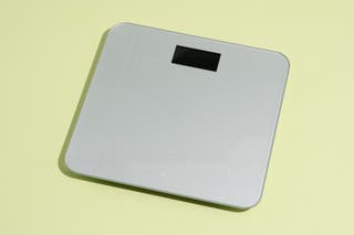 Our pick for best bathroom scale in a smaller size, the Greater Goods AccuCheck Scale, shown in front of a yellow background.