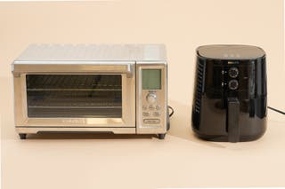 A convection toaster oven next to an air fryer with a basket handle.