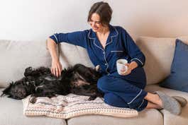 Woman wearing the navy Eberjey Gisele PJ Set sitting on a couch with a dog.