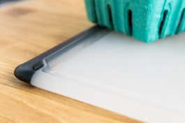 A closeup of the black grippy feet on the left and right side of a plastic OXO cutting board.