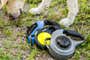 A dog sniffs the grass next to three retractable leashes.