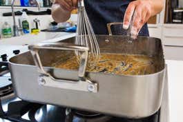 A person deglazing the mulitclad pro roasting pan over two burners.