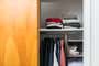 A shot of a closet containing several shirts and sweaters set up with several closet organizing implements.