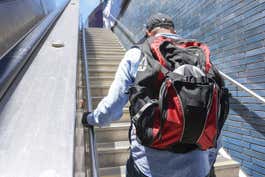 A person with the Arkel Bug on their back, walking up a flight of stairs.