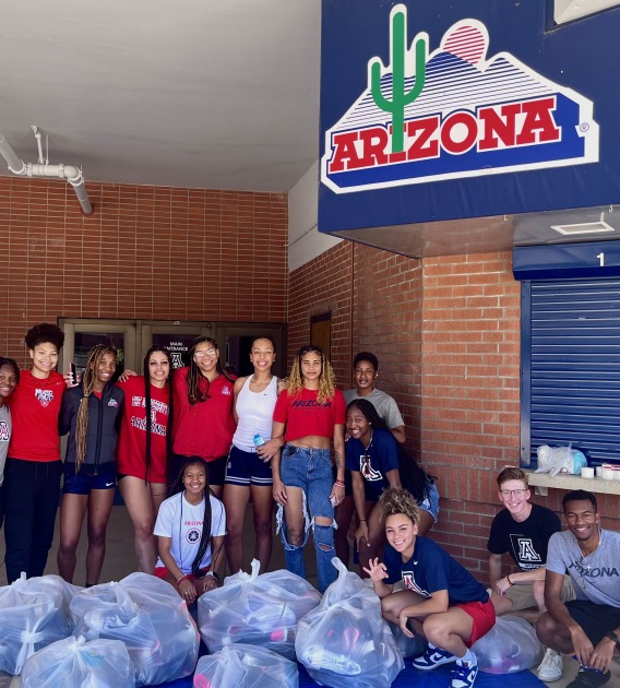 students posing with several bags of donated shoes