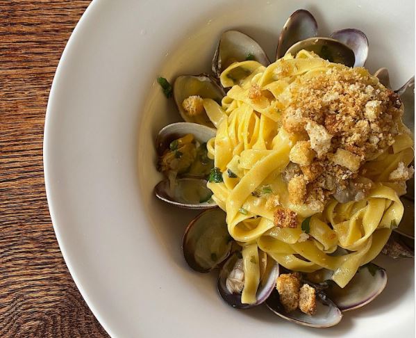 A bowl of flat pasta with clam shells.