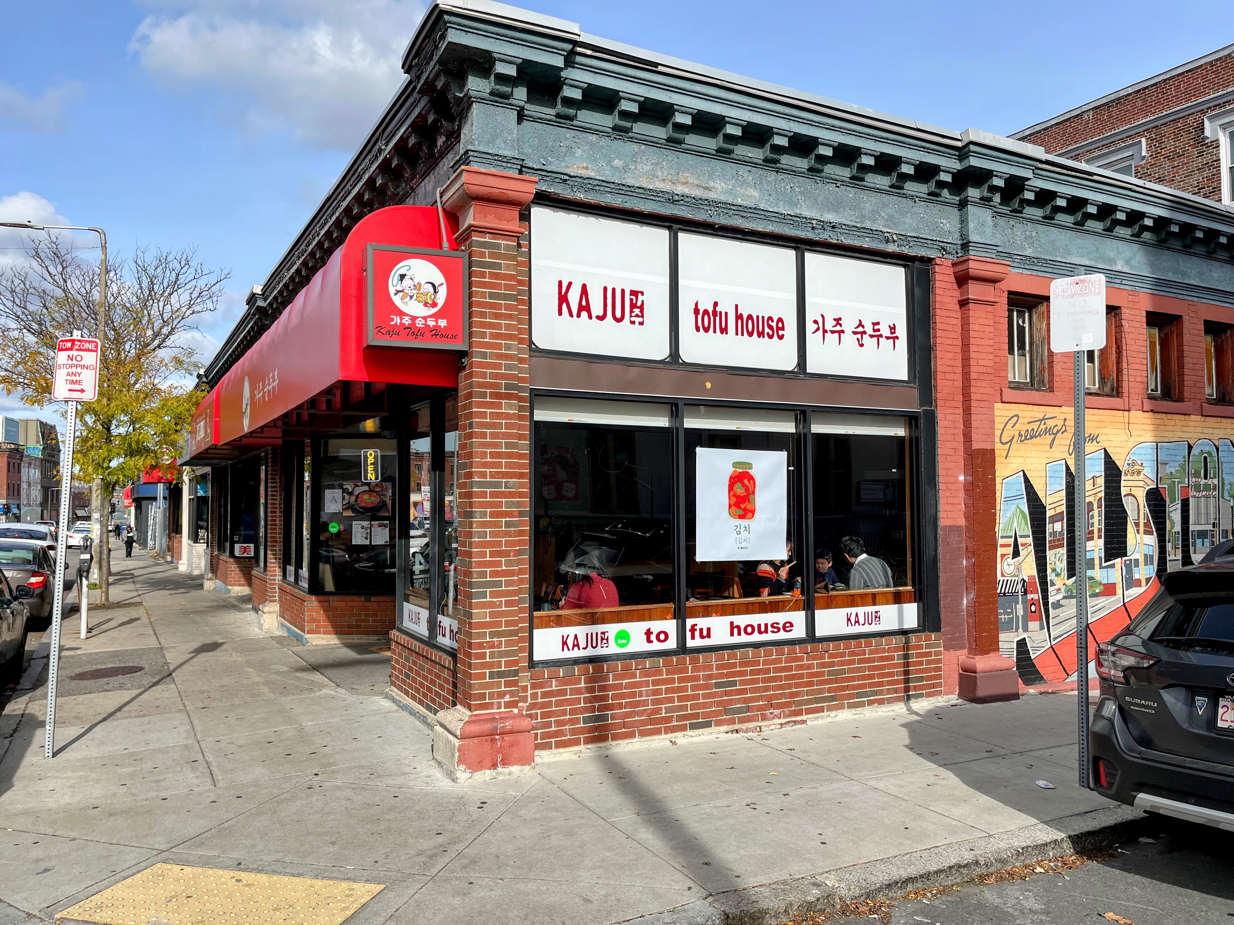 An exterior of a restaurant with red brick walls and white signage with red lettering.