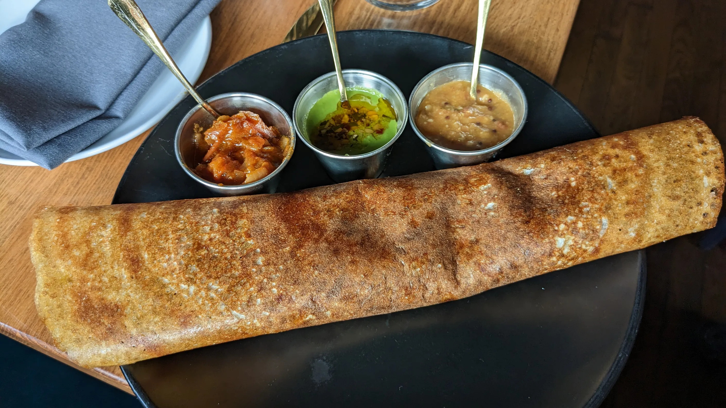 A dosa with condiments on a plate.