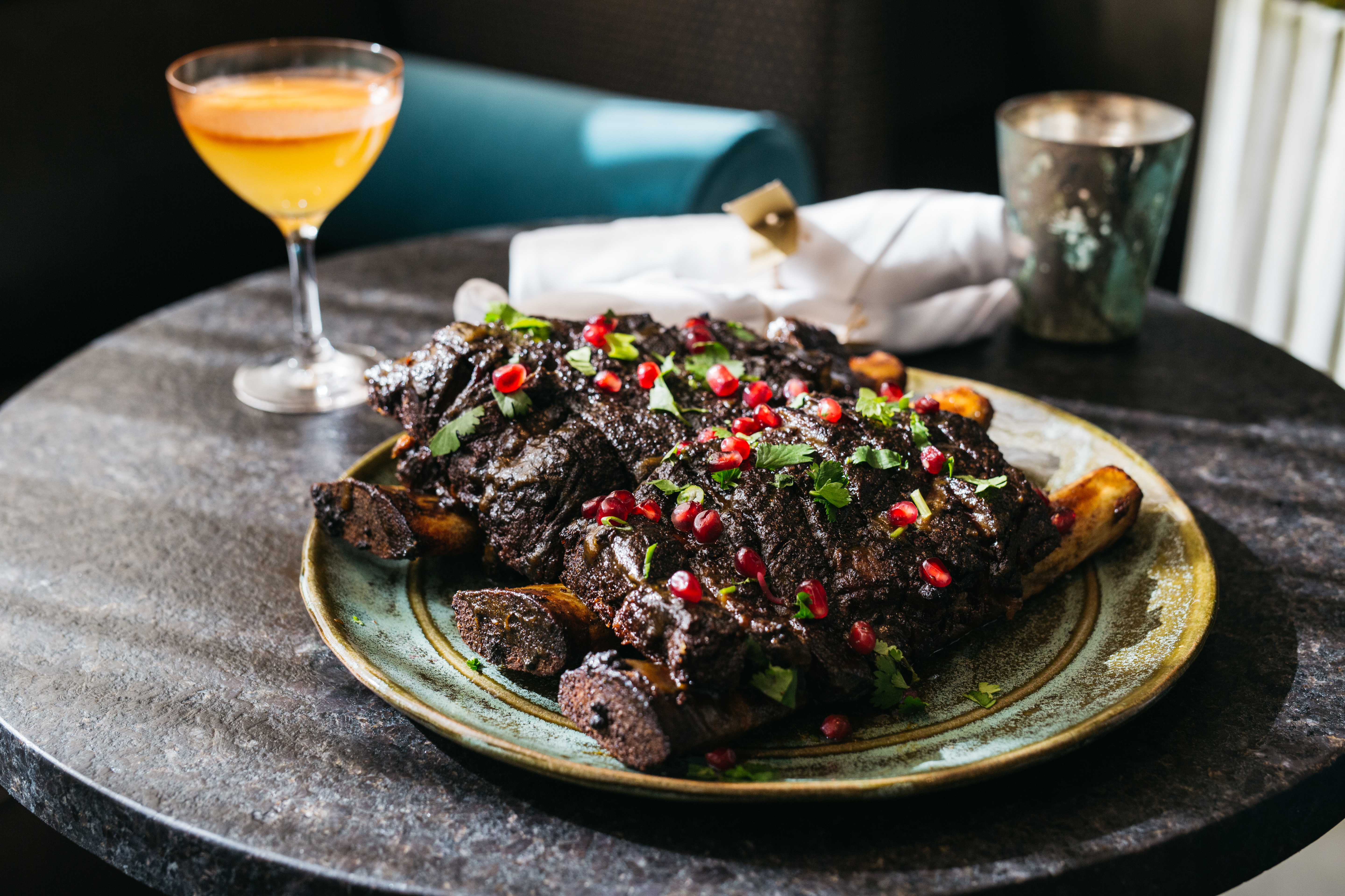 Rumi’s Kitchen’s three-bone pomegranate short ribs decorated with herbs and pomegranate seeds.