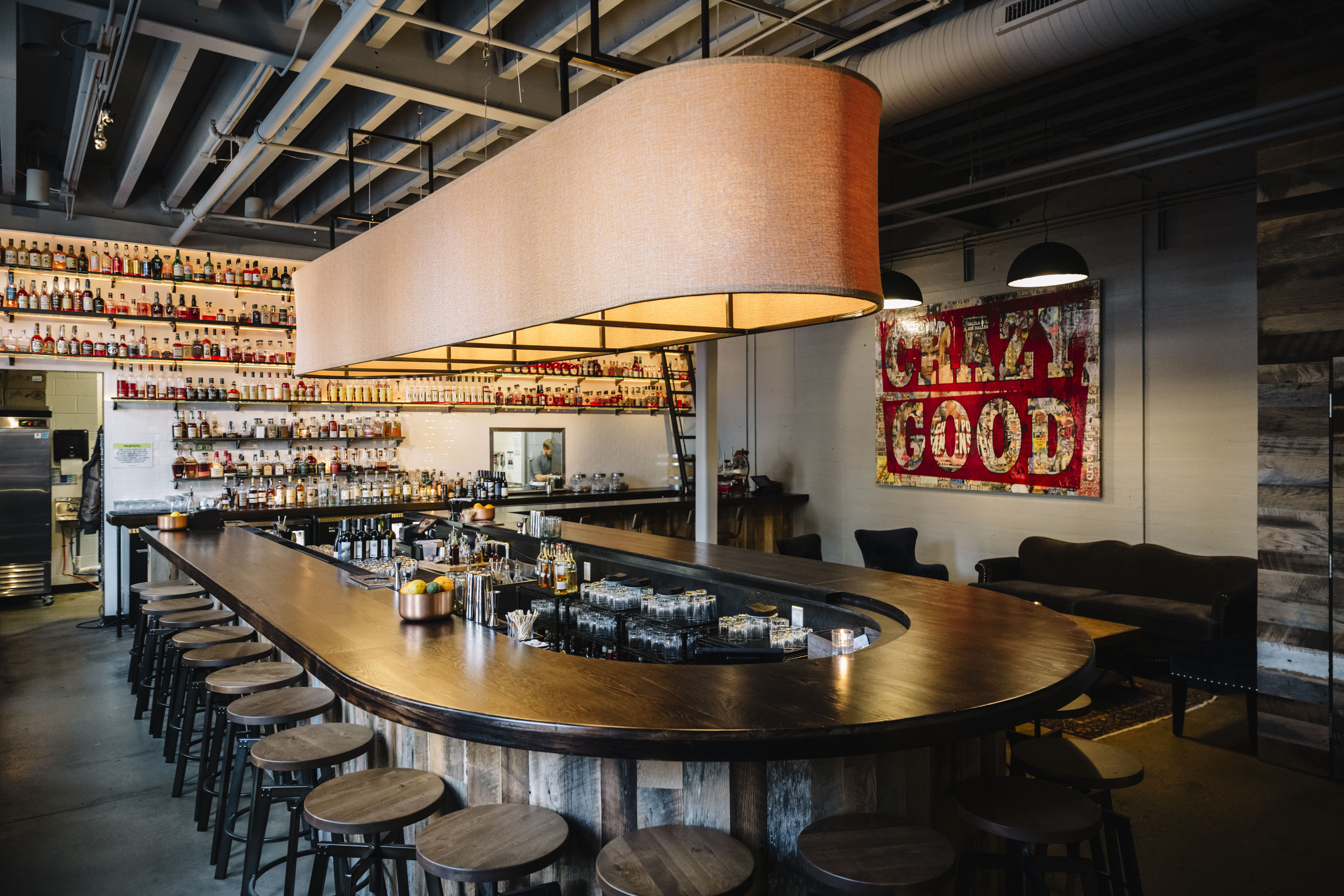 Interior view of a whiskey bar in Nashville with an oval-shaped bar foregrounding a stacked whiskey shelf display.