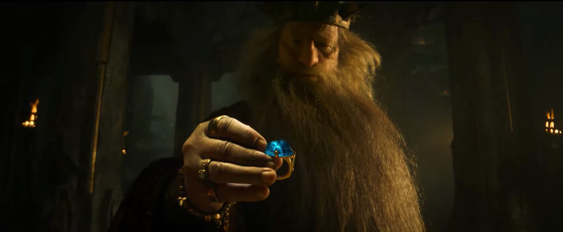 King Durin picks up a golden ring with a huge blue gem set into it in The Lord of the Rings: The Rings of Power.