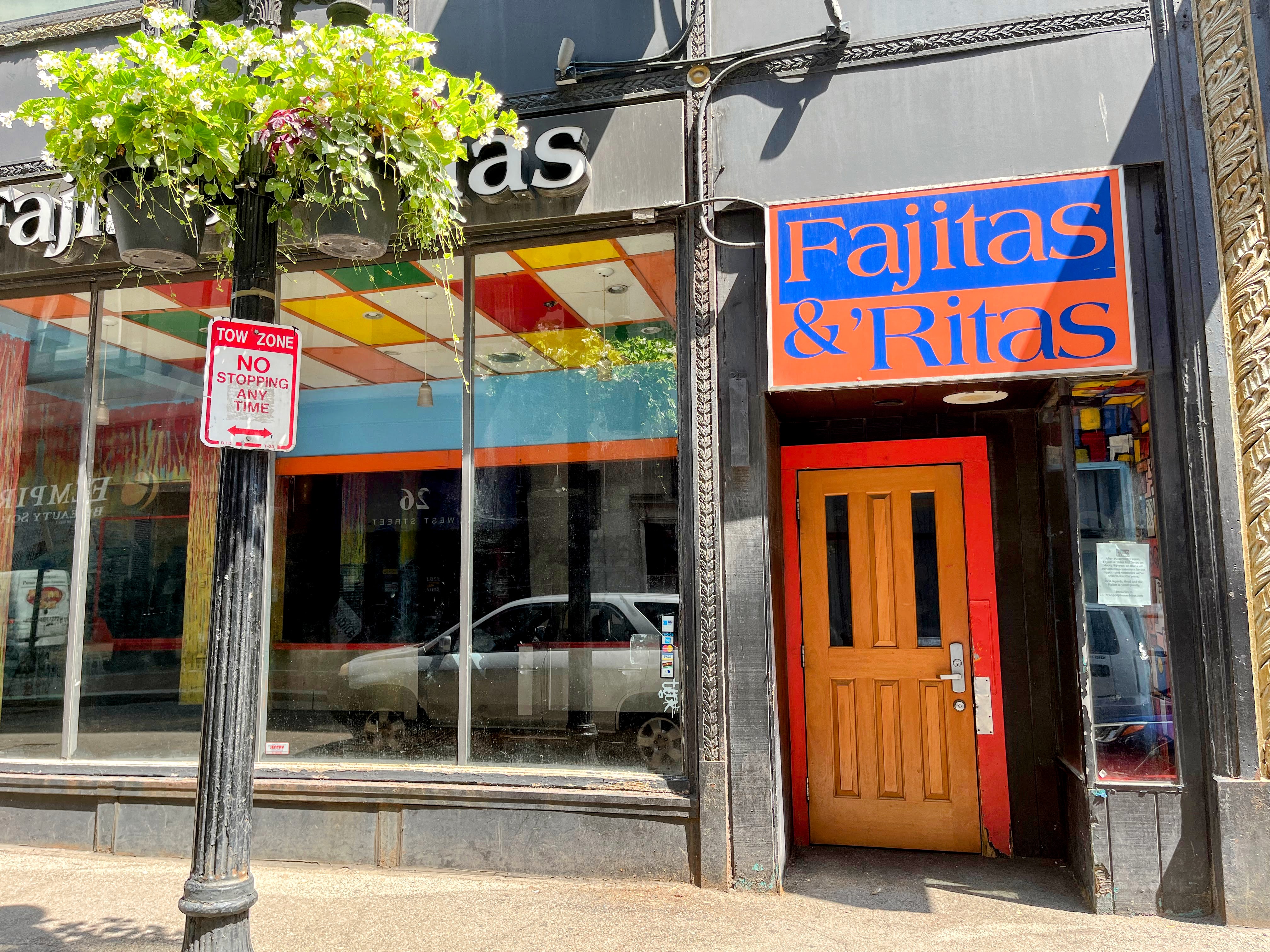 The exterior of a closed-down restaurant with a colorful blue and orange sign spelling out “Fajitas &amp; ‘Ritas” over an orange and red door.