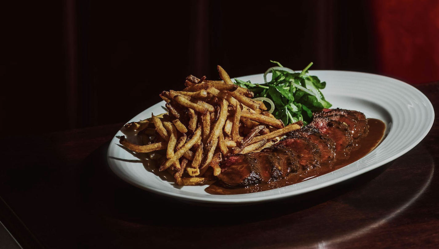 A plate of sliced red steak and crispy french fries.