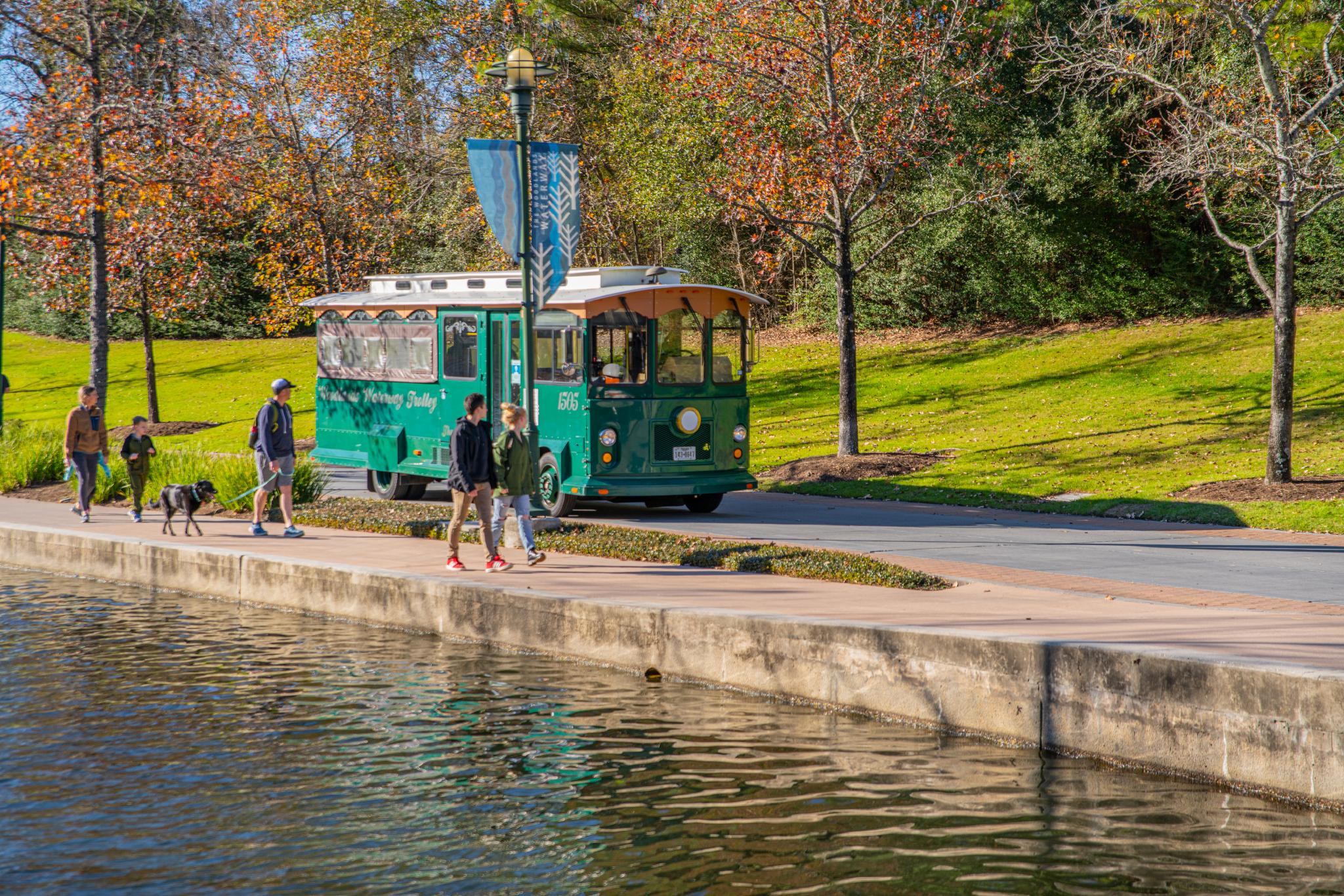 A trolley travels through The Woodlands along the Waterway.