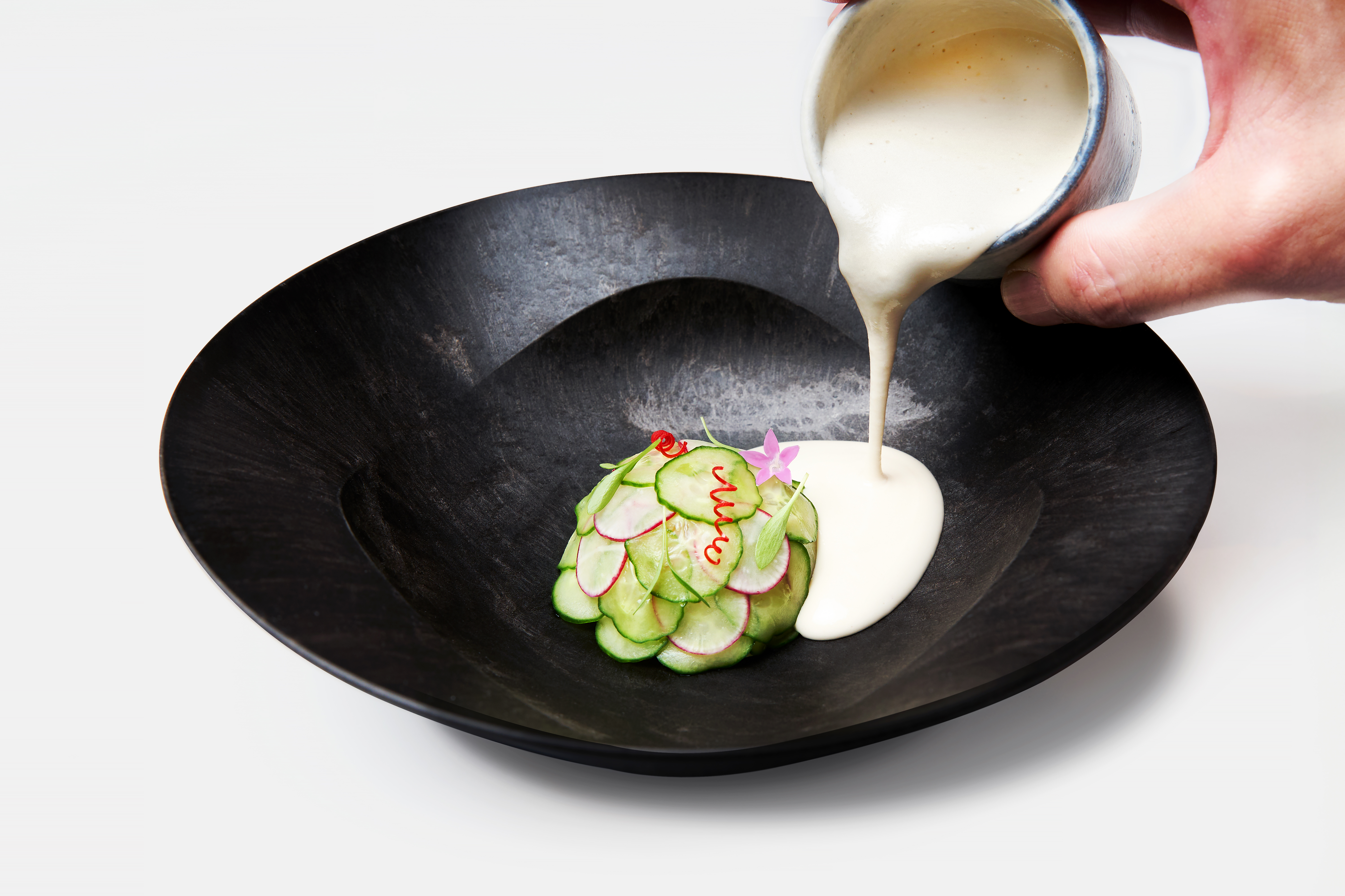 A black bowl shows off a cucumber dish. 