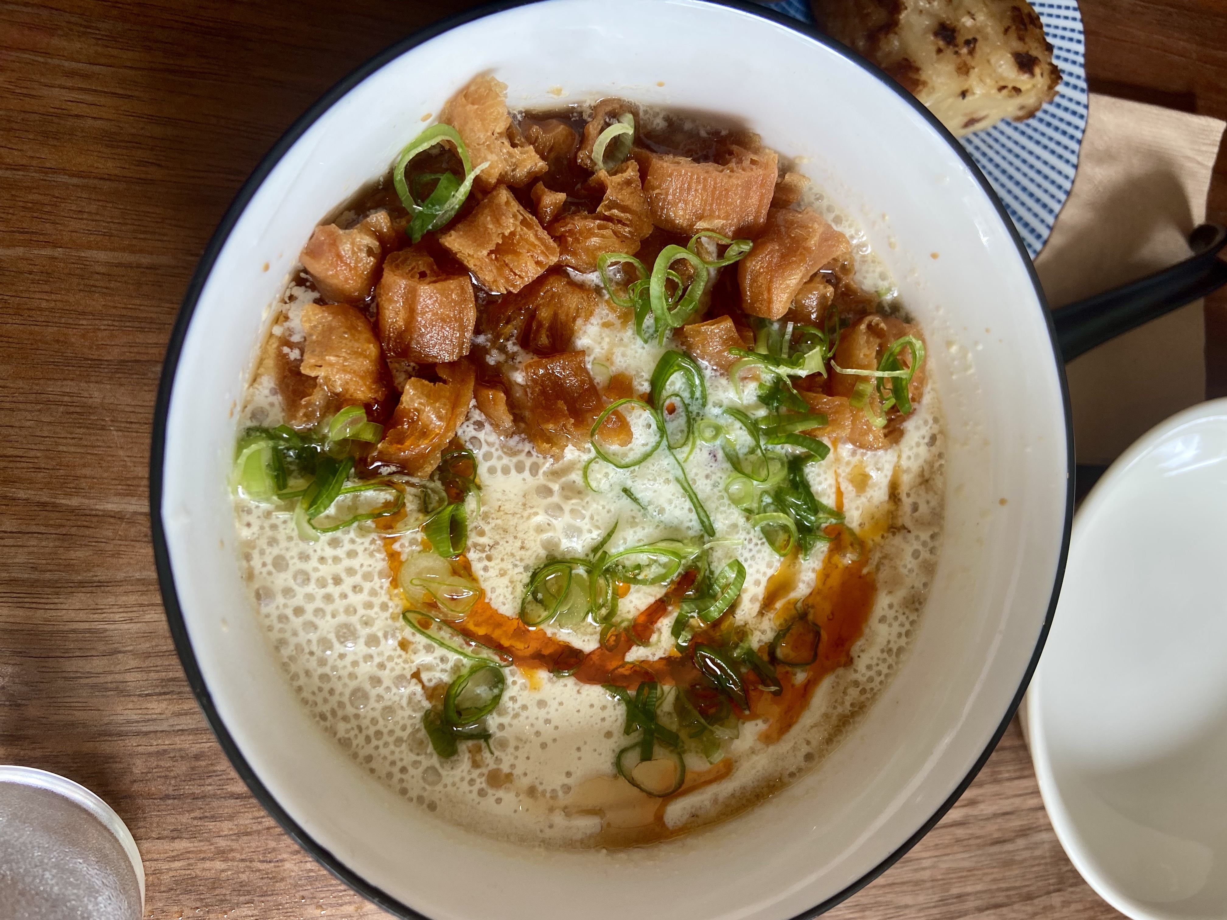 An overhead shot of a bowl of soy milk with pork floss and scallions. 