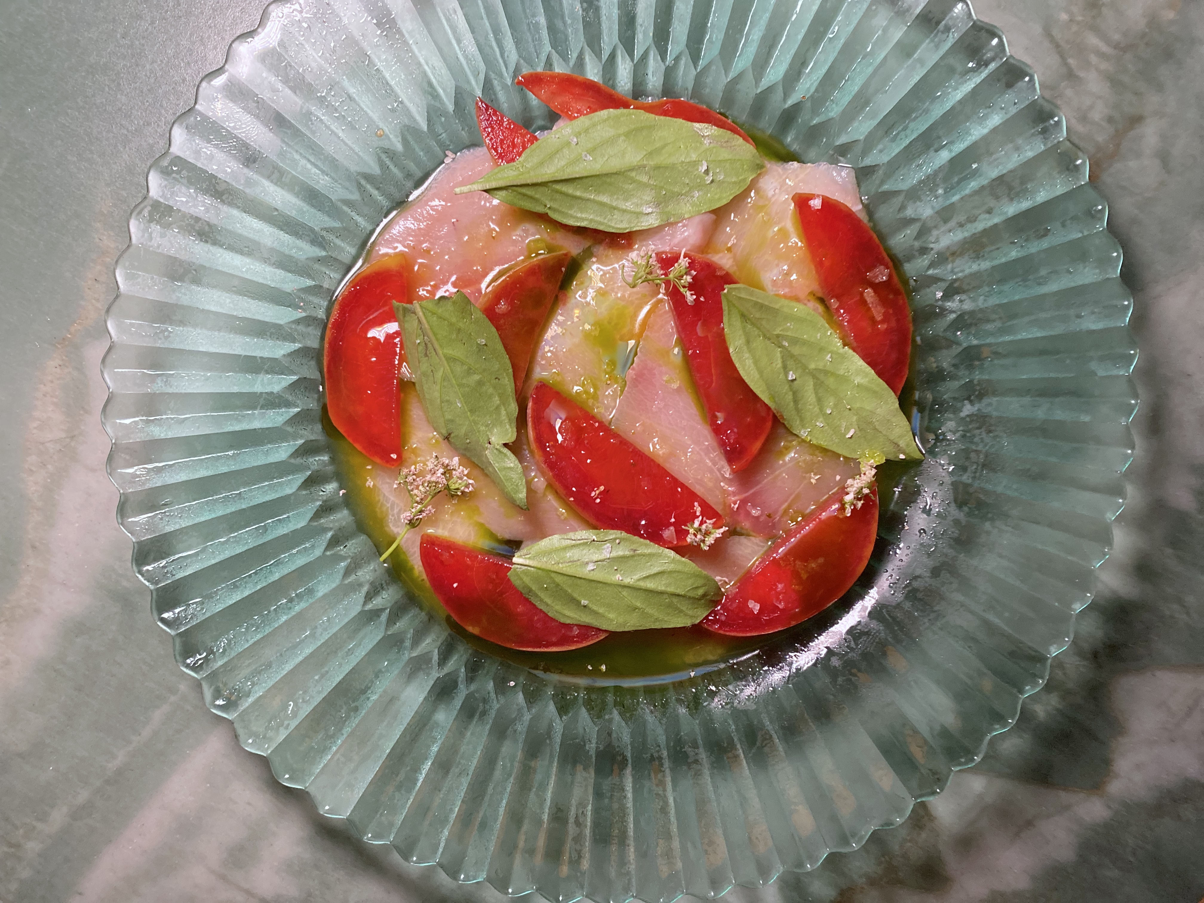 A translucent blue plate with slices of hamachi crudo, plum, and basil at the Benjamin in Hollywood.