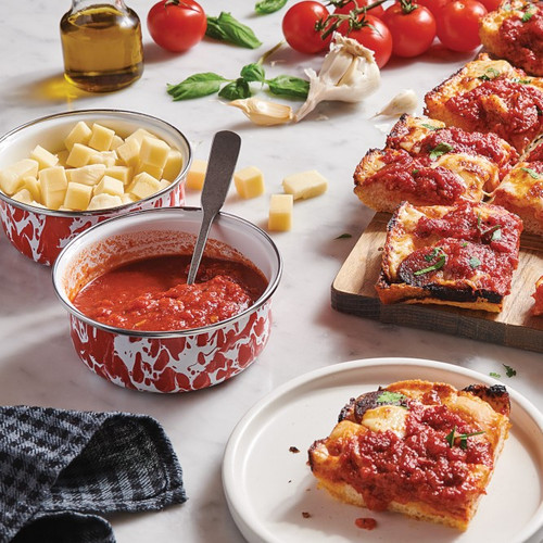 Prep Bowls on tabletop with pizza and pizza ingredients.