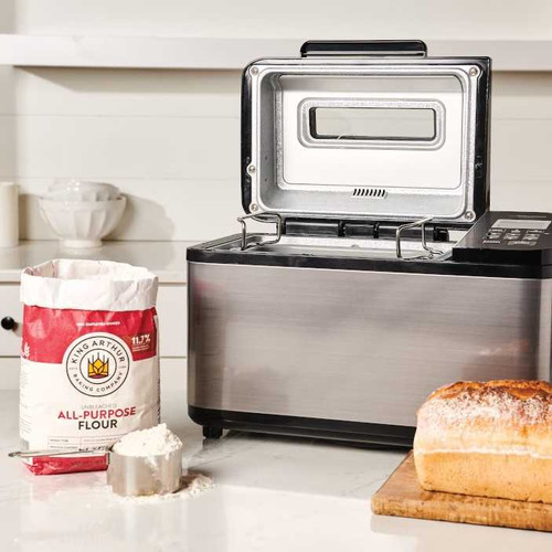 Zojirushi Home Bakery Virtuoso Plus Bread Machine on countertop with baked bread and bag of King Arthur All-Purpose Flour