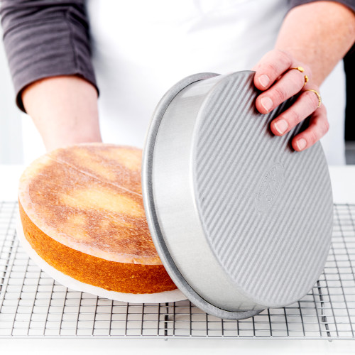 A yellow cake being removed from a cake pan with Round Parchment Paper to help with easy removal.