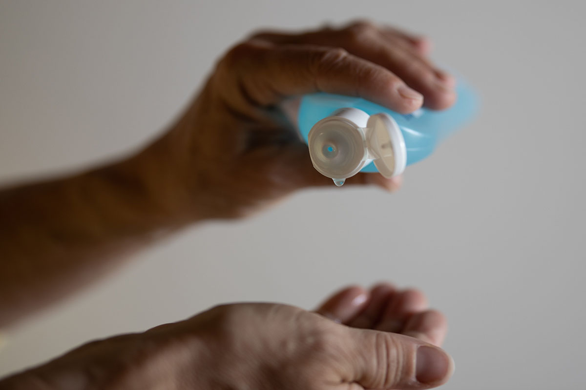 A person squeezing a bottle of hand sanitizer 