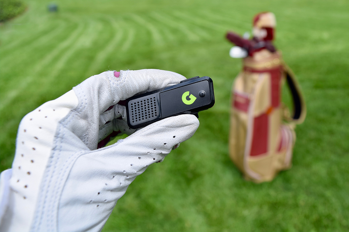 A person wearing a golf glove, holding a range finder. 