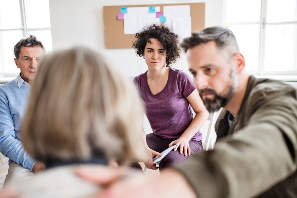 Men and women sitting in a circle during group therapy