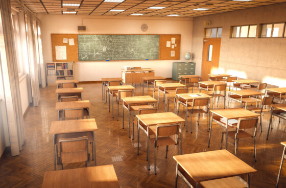 Empty classroom from the back with desks facing blackboard