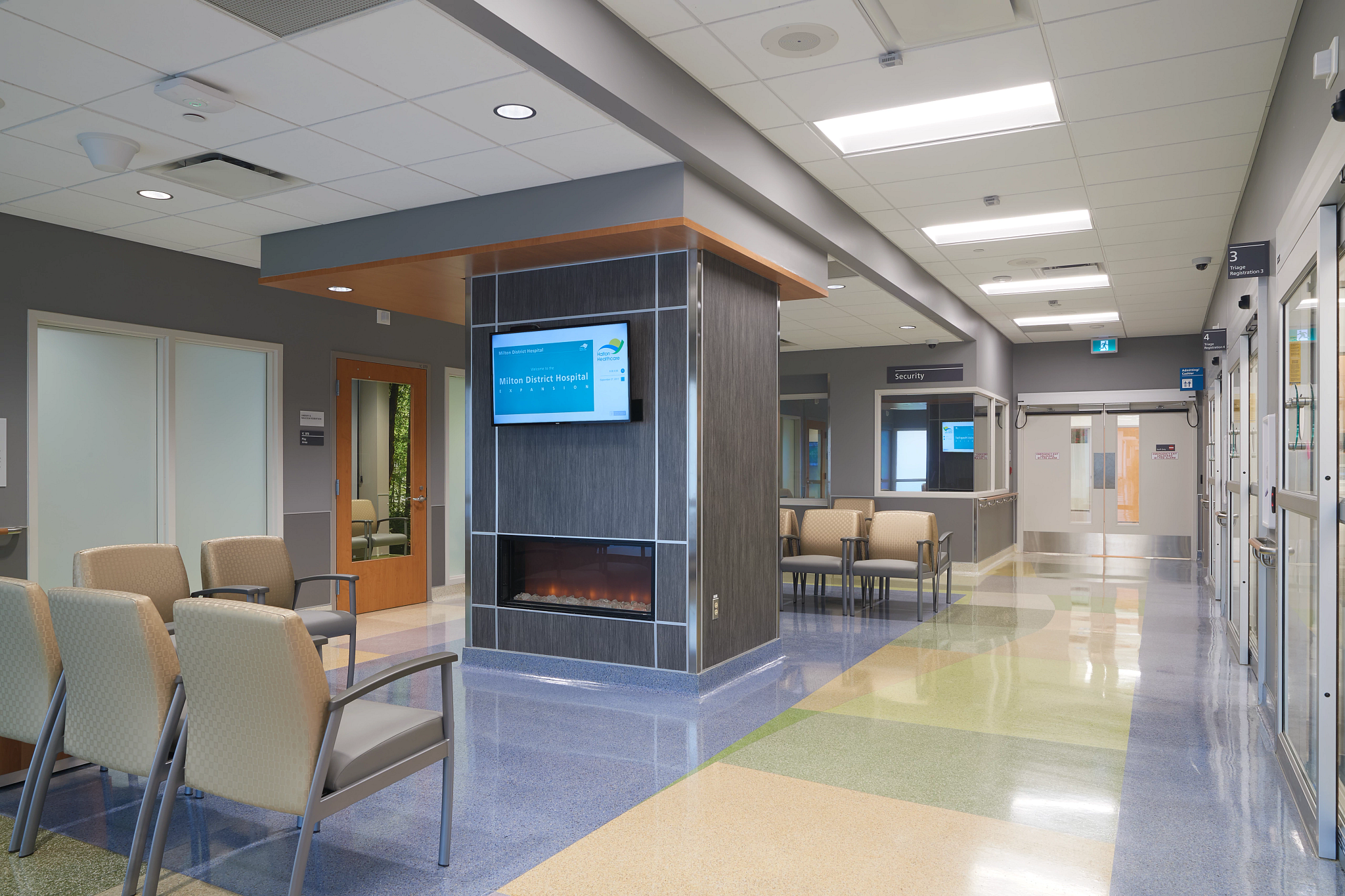 A hospital waiting room with a fireplace and tv.