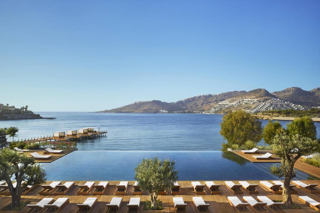 a view of the water at a resort with lounge chairs at The Bodrum EDITION in Yalıkavak