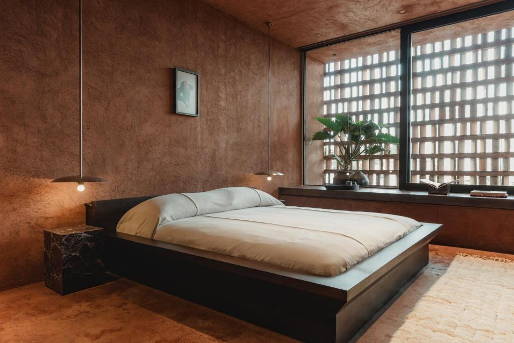 a bedroom with a bed and a large window at Further Hotel in Canggu