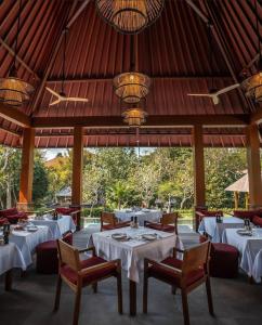 a restaurant with white tables and chairs and a ceiling at La Reserve 1785 Canggu Beach in Canggu