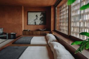 a bedroom with two beds and a window at Further Hotel in Canggu