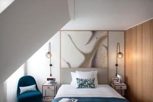 a bedroom with a bed and a blue chair at Storchen Zürich - Lifestyle boutique Hotel in Zurich