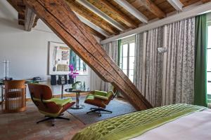 an attic bedroom with a bed and chairs and a desk at Storchen Zürich - Lifestyle boutique Hotel in Zurich