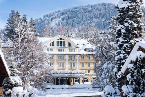 un grande edificio nella neve con alberi innevati di Le Grand Bellevue a Gstaad