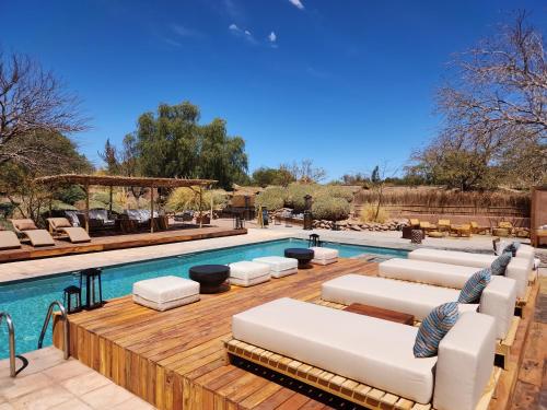 a swimming pool with white lounge chairs next to it at Our Habitas Atacama in San Pedro de Atacama