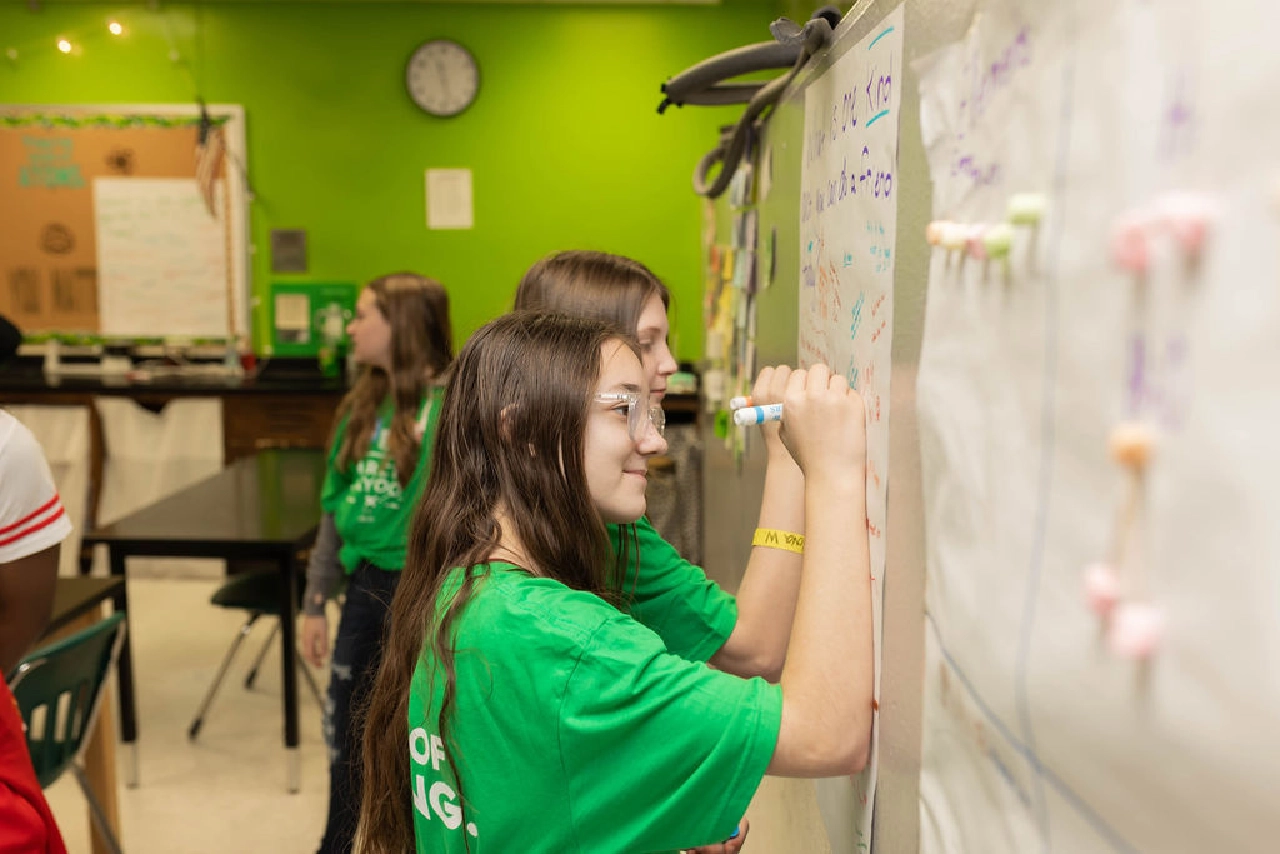 Students writing on whiteboard during activity