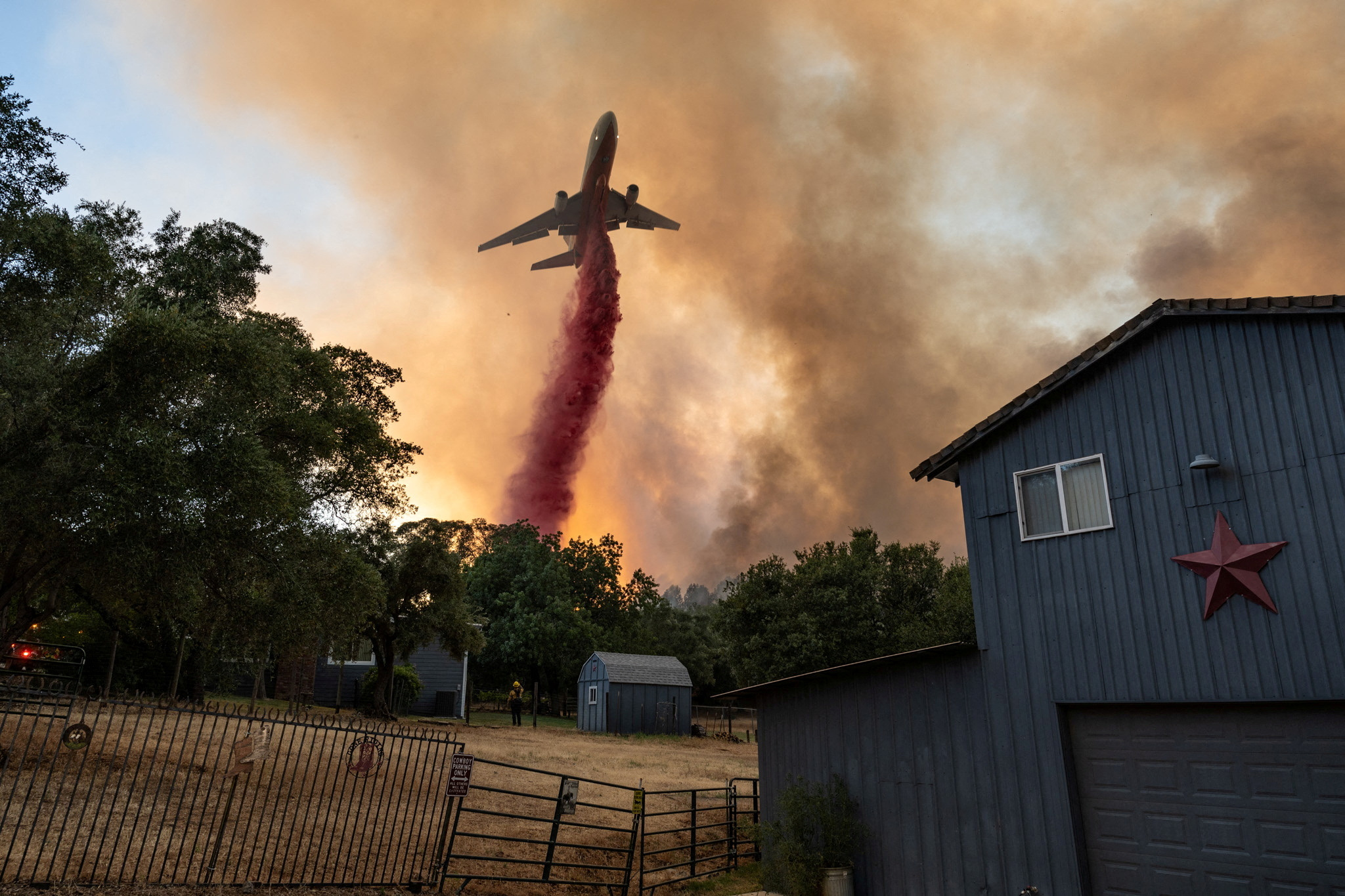 Firefighters drop retardant next to a house as they battle a wildfire in a canyon in Oroville